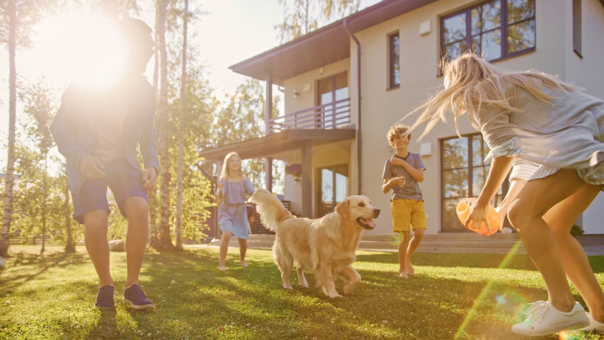 Family playing with their dog outside their new home